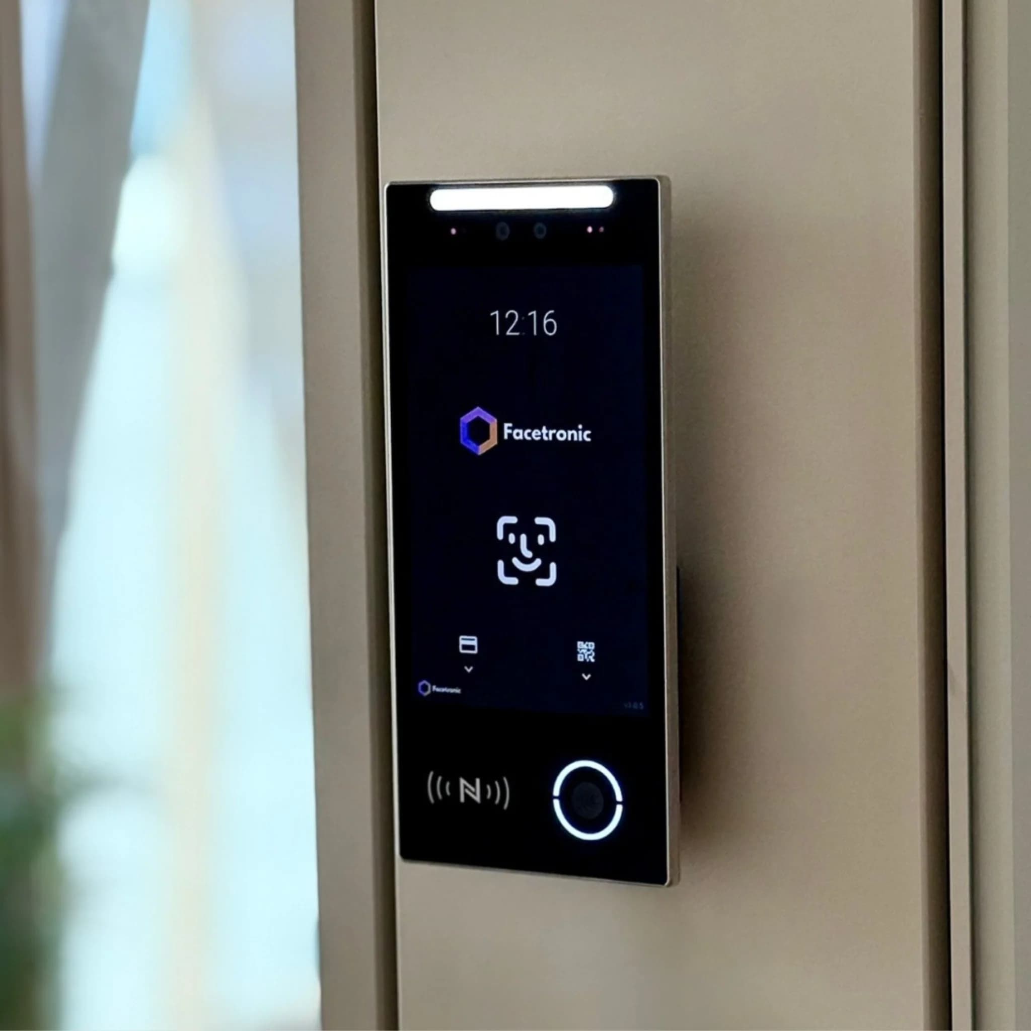 IDA Reader mounted on a wall, its display showing the Facetronic logo and the check-in options